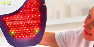Person holding a red LED light therapy device.