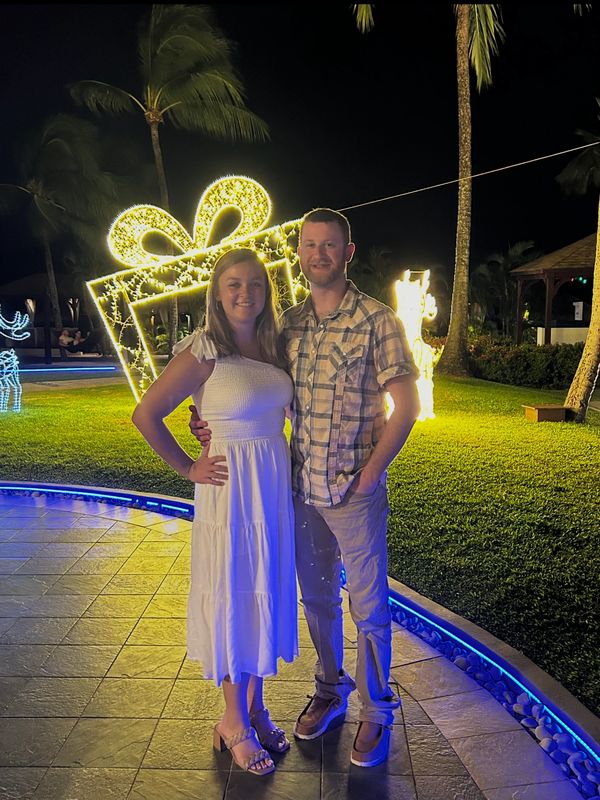Couple posing at night near illuminated holiday decorations outdoors.