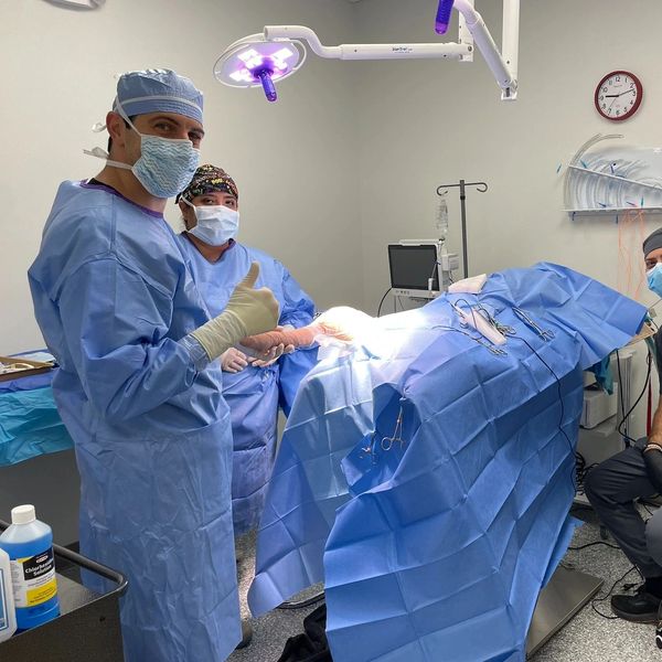 Surgeons in an operating room giving a thumbs up.