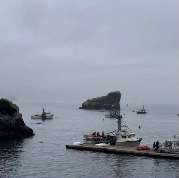 Miss Phyllis docked on a calm, foggy sea near rocky islands.