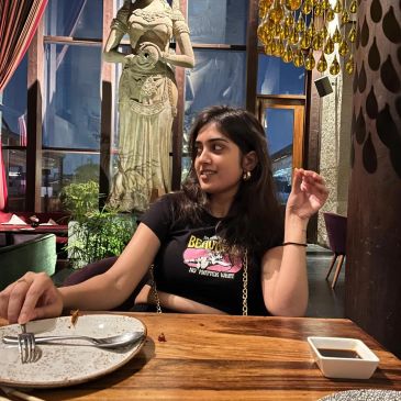 Young woman sitting at a restaurant table with a sculpture in the background.