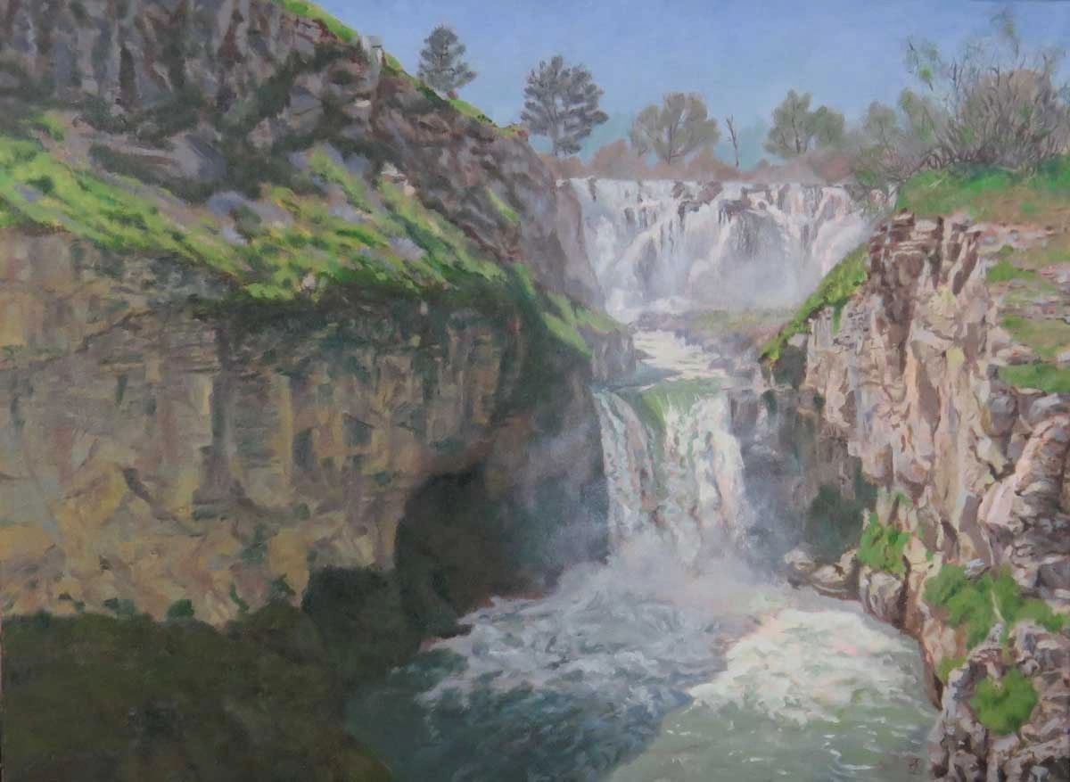A scenic waterfall cascading between rocky cliffs with greenery and trees.