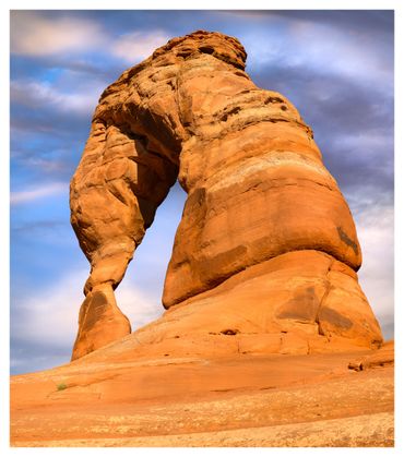 Natural sandstone arch against a vibrant sky.