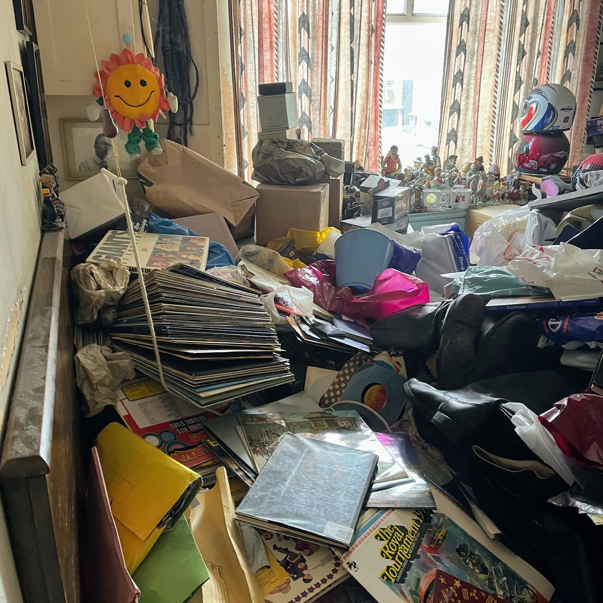 Cluttered room filled with vinyl records, papers, and various items scattered around.