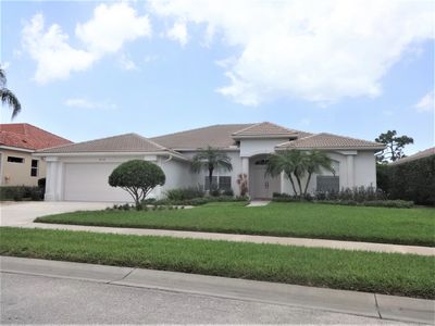 Single-story house with a well-maintained lawn and palm trees.