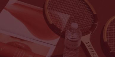 Two wooden tennis rackets and a bottle of water on a table.