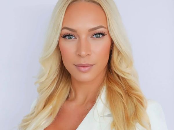 Professional portrait of a confident woman with long blonde hair in a white blazer.