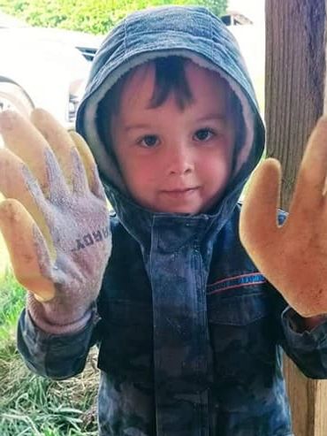 A sweet child helping with some gardening.  His gloves are as big as he is....