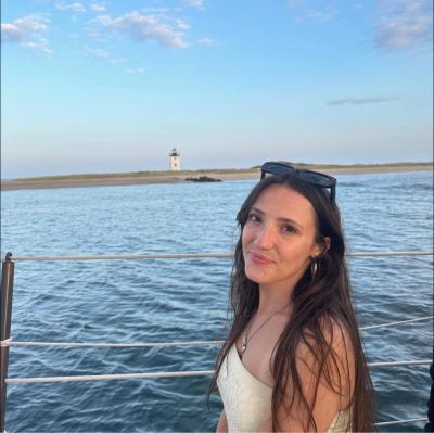 Young woman smiling on a boat with a lighthouse in the background.