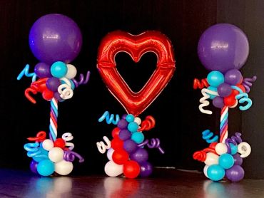 Colorful balloon decorations with a red heart-shaped balloon centerpiece.