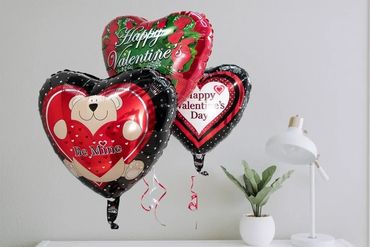 Heart-shaped Valentine balloons with greetings and a teddy bear design.