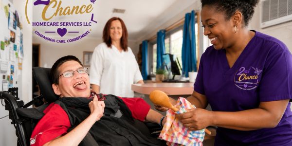 Caregiver smiling while attending to a happy person in a wheelchair.