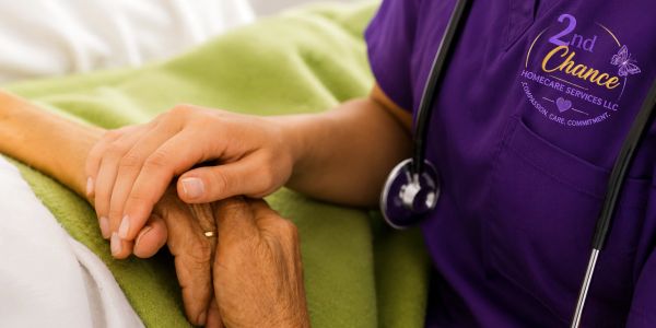 Healthcare worker holding elderly patient's hand.