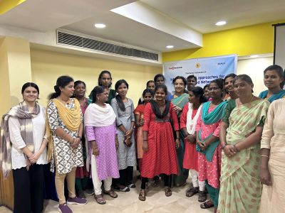 Group of women posing indoors around a banner.