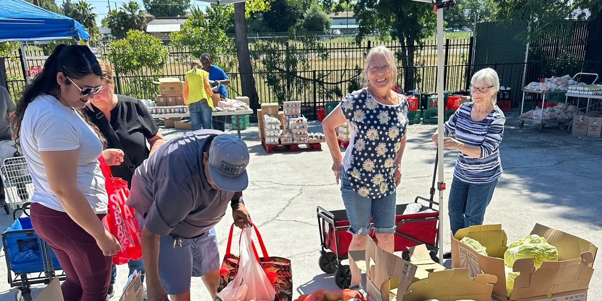 Community members gather to distribute fresh produce at an outdoor food market.