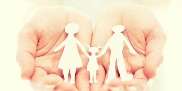 Hands holding paper cutouts of a family of three.