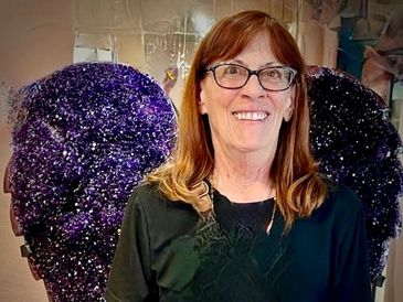 Woman smiling with purple glitter angel wings.