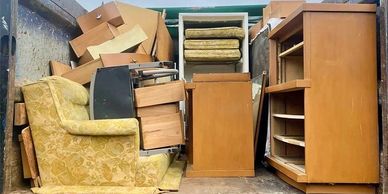 Stack of old furniture and boxes in a storage space.