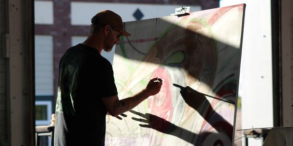 Larry White painting a mixed media live art piece at The Hub in Port Angeles WA