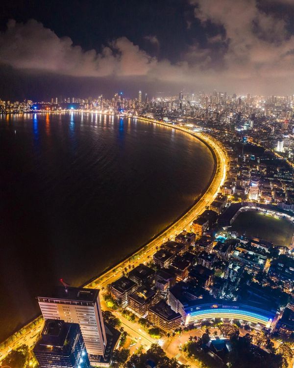 Aerial night view of a city coastline with illuminated roads and buildings.