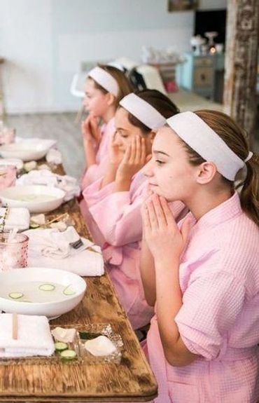 Girls in pink robes enjoying a spa facial treatment together.