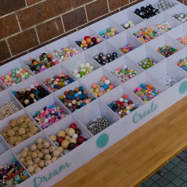 Organized colorful beads in a craft tray labeled Dream and Create.