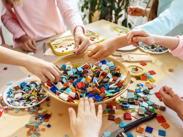 Hands selecting colorful mosaic tiles for crafting.