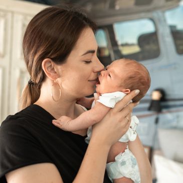 Mother lovingly kisses her newborn baby.