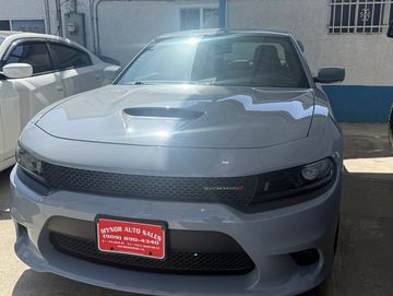 A silver Dodge Charger parked outdoors with a red dealership license plate.