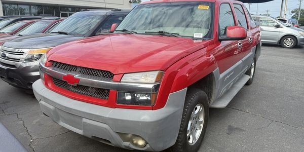 Red Chevrolet Avalanche pickup truck parked in a lot.
