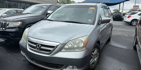 Silver Honda minivan parked in a lot with other vehicles.
