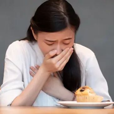 Woman feeling nauseous while looking at a muffin.
