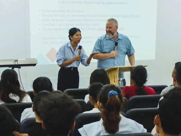 Two presenters speaking in front of an audience during a seminar.