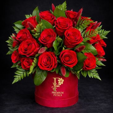 Elegant bouquet of red roses in a red box with green foliage.