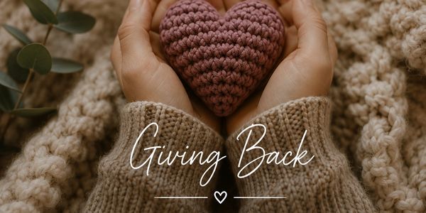 Hands holding a knitted heart with 'Giving Back' text.