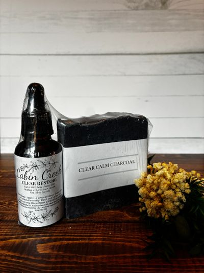 Natural skincare products with charcoal soap and flower on wooden surface.