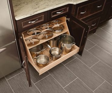 Kitchen cabinet with organized pots, pans, and lids on sliding shelves.