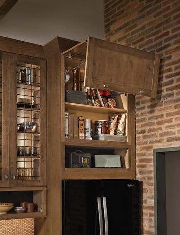Open wooden kitchen cabinet showing organized pantry items and snacks.