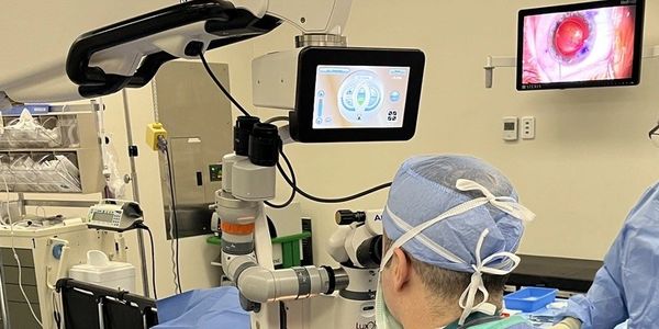 Surgeon performing eye surgery using advanced equipment.