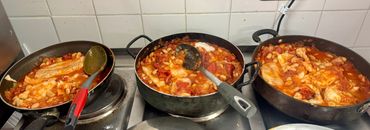 Three pans of spicy Korean rice cakes cooking on a stove.