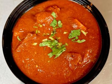 A bowl of rich, red curry garnished with fresh cilantro.