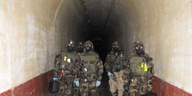 Four soldiers in full gear stand in a tunnel.