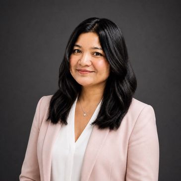 Professional woman with dark hair, wearing a light pink blazer and white blouse, smiling gently.