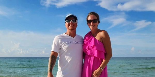 Couple standing on the beach with the ocean in the background.