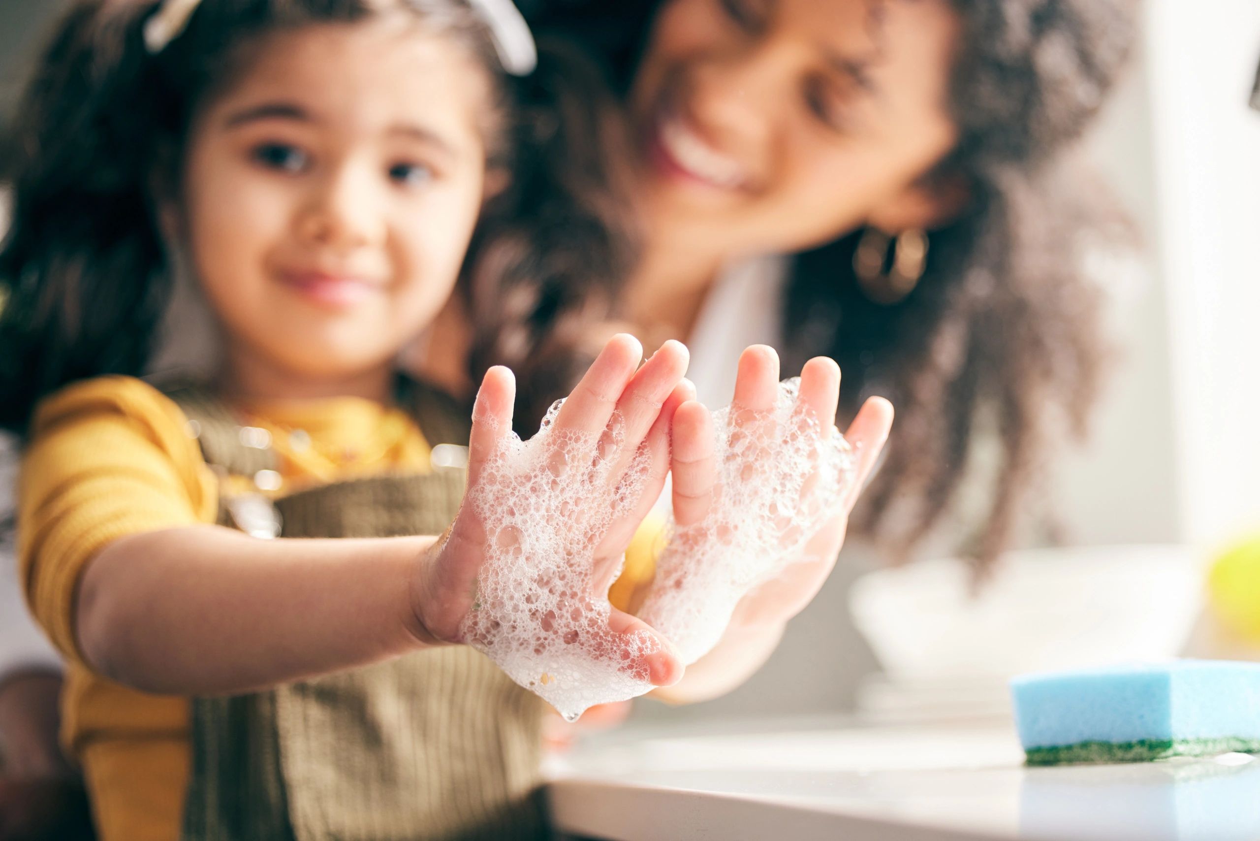 close up on a child's hands covered in soap bubbles made with soft water