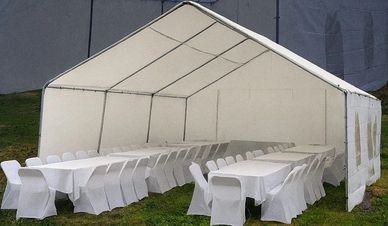 White tent with covered chairs and tables set on grass.