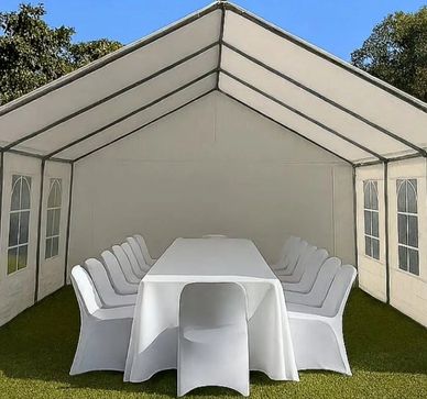 White tent with a long table and white-covered chairs inside.