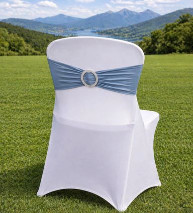 White chair with blue sash and decorative buckle on a grassy field.