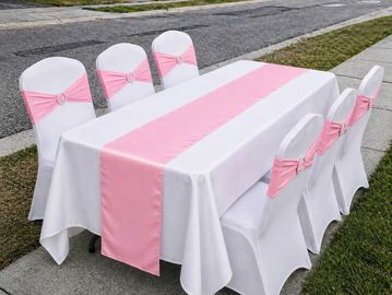 Outdoor table setup with white and pink decorations.
