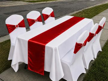 White chairs and table with red sashes and runner.